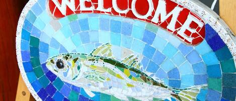 A mosaic welcome sign with a fish design.
