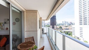 A balcony with a table and chairs, a sliding glass door, and a city view. - ADD Berrini (São Paulo)