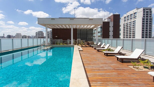 A rooftop pool with lounge chairs and a view of the city skyline. - ADD Berrini (São Paulo)