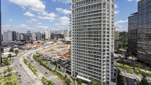 A high-rise building with multiple balconies, surrounded by a busy urban street and other buildings. - ADD Berrini (São Paulo)