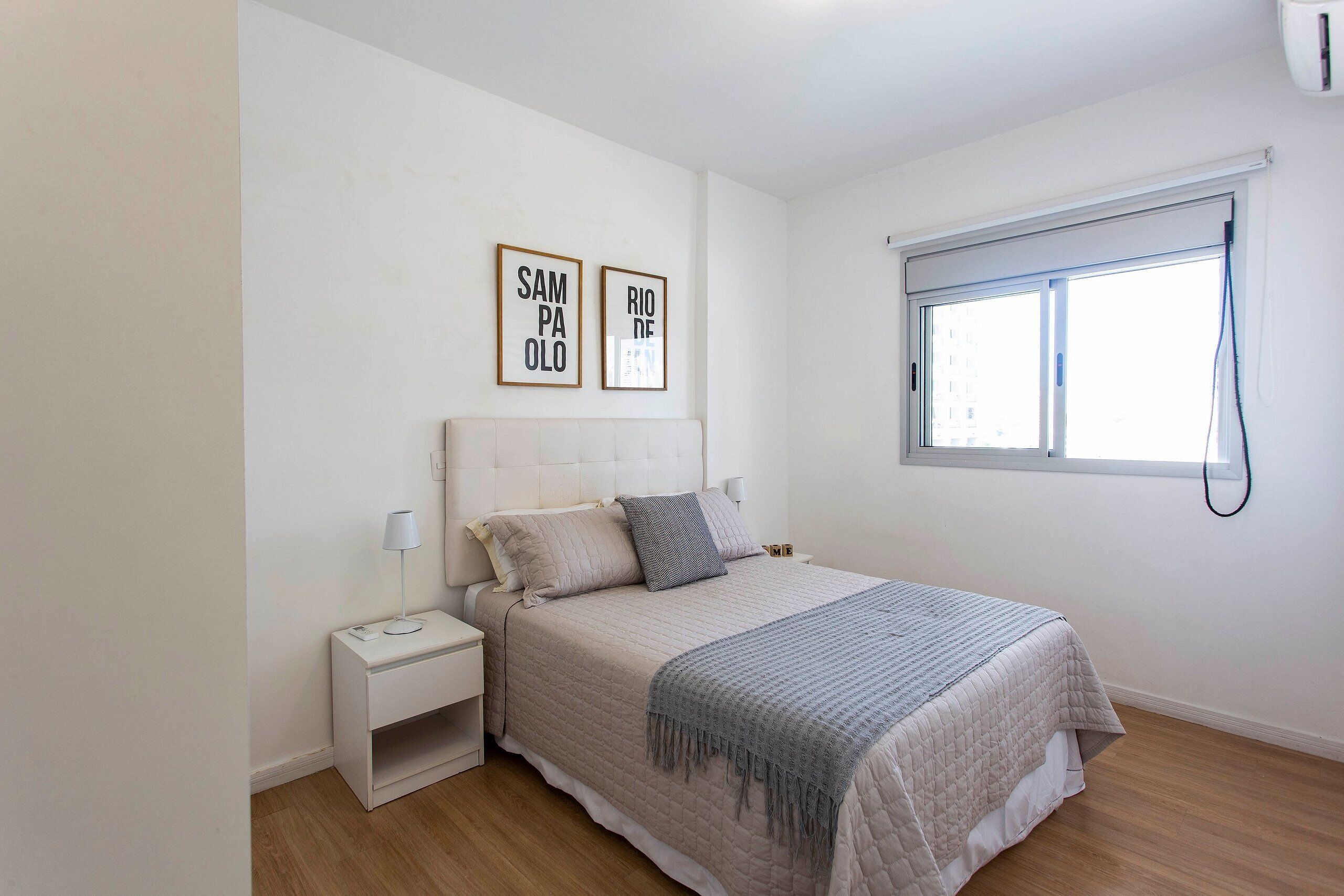 Quarto com cama, mesa de cabeceira, decoração na parede e janela.