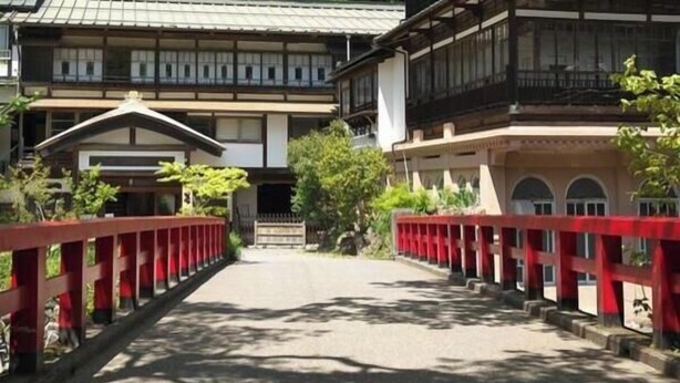 Un edificio tradicional con un puente rojo que conduce a la entrada.