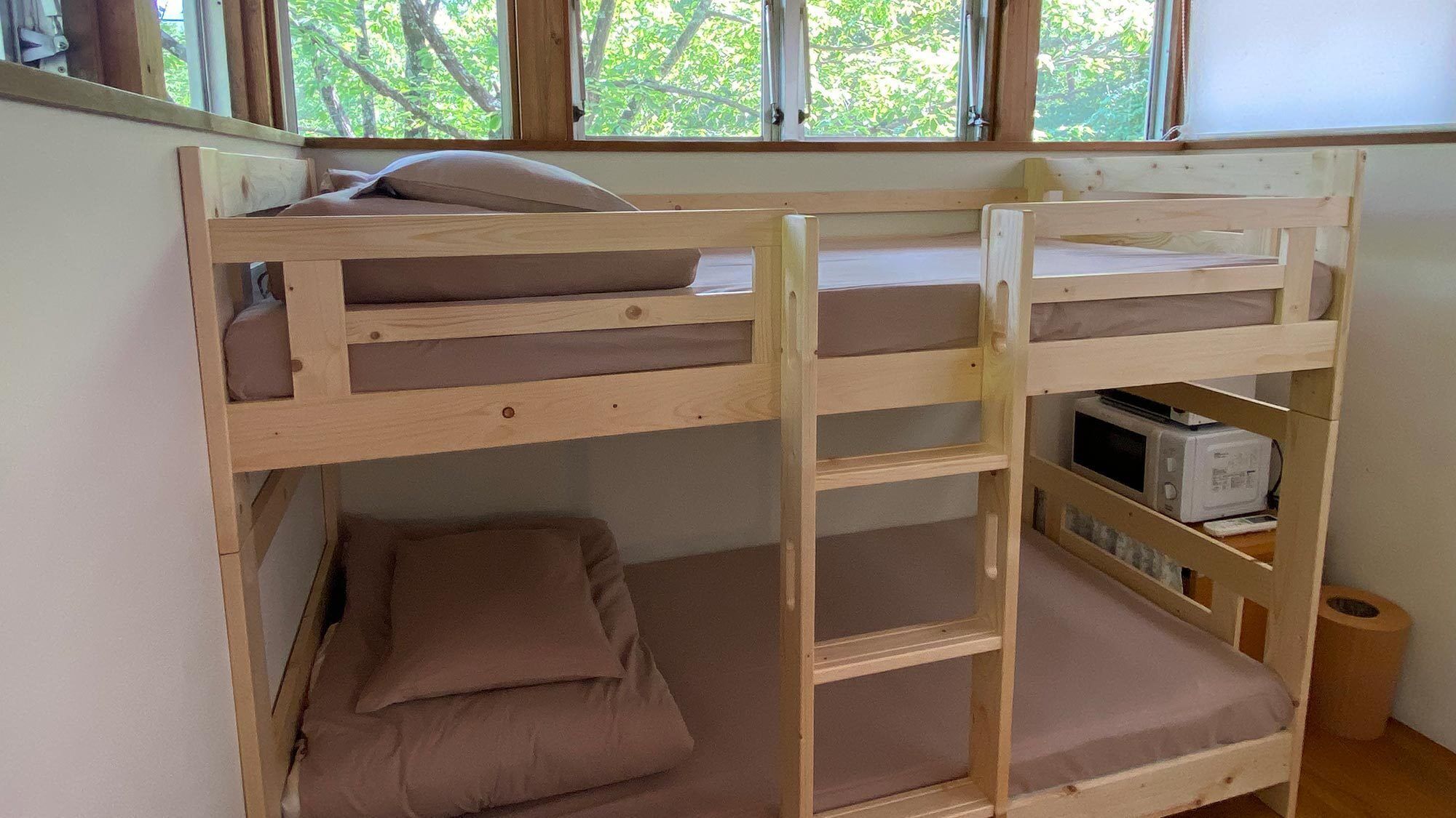 Una cama litera con un microondas y un cubo de basura en la habitación.