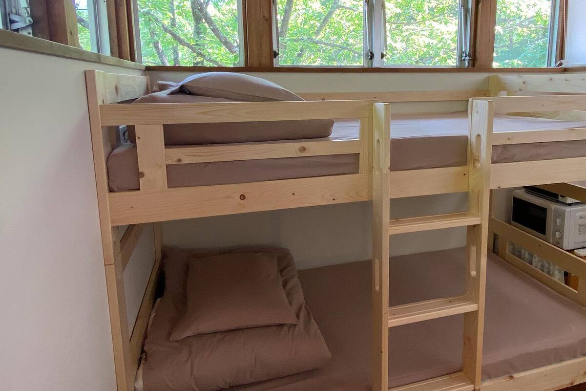 Una cama litera con un microondas y un cubo de basura en la habitación.