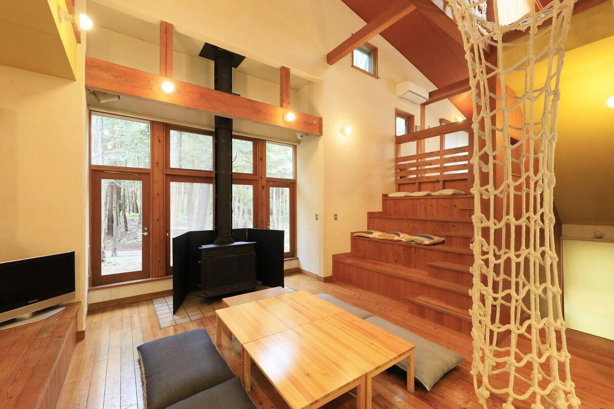 Interior de madera con chimenea, televisor y escalera.