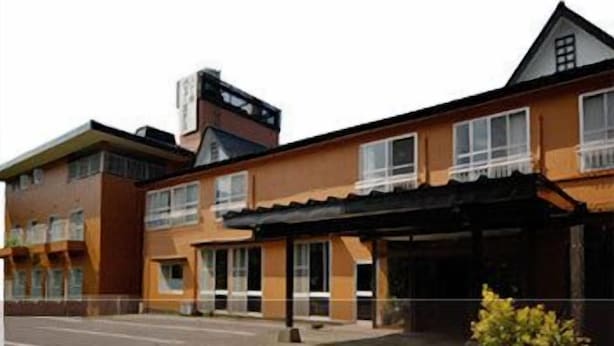 Un hotel a più piani con tetto piatto, ampie finestre e una zona esterna coperta.