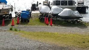 A boat docked at a marina with a trailer and covered items nearby. - Kamisuwa Onsen Minshuku Ahiru (Suwa)