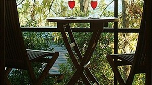 A wooden table with two chairs, a glass of red wine, and a view of the sea through a window. - Hanareyado Yumenoya (Ito)
