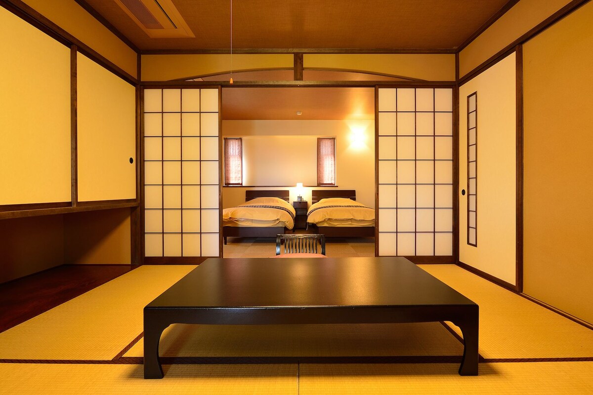 Ett traditionellt japanskt rum med tatamimattor på golvet, ett lågt bord och skjutdörrar.