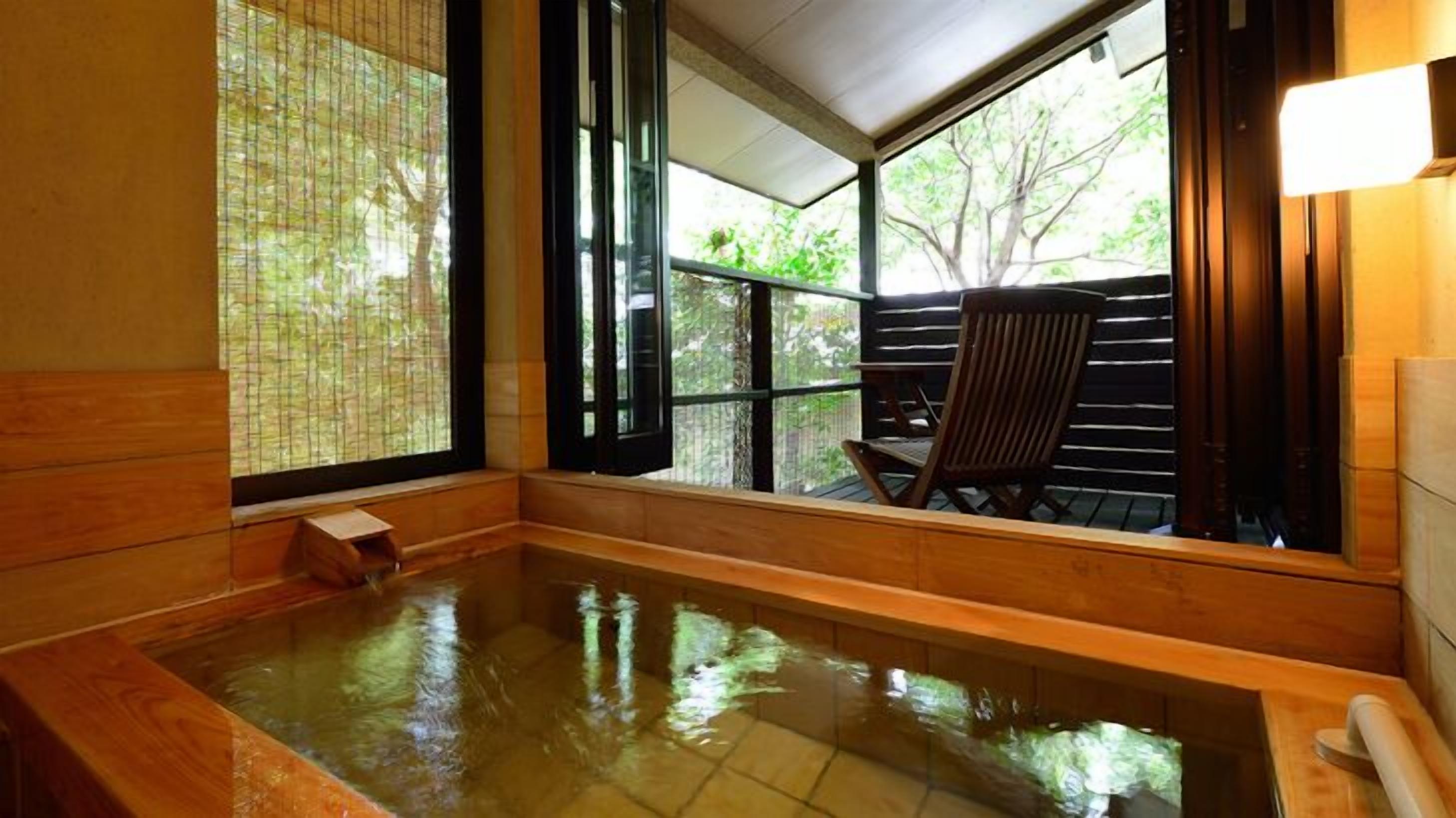 A hot spring bath with wooden walls and large windows.