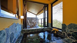 A stone-lined hot tub with a wooden deck and outdoor seating. - Hanareyado Yumenoya (Ito)