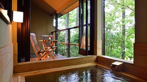 A hot tub area with wooden chairs and a view of trees through large windows. - Hanareyado Yumenoya (Ito)