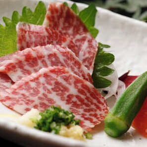 A plate with sliced meat, green vegetables, and a small portion of a yellowish substance. - Kurokawa Onsen Iyashi no Sato Kiyashiki (Minamioguni)