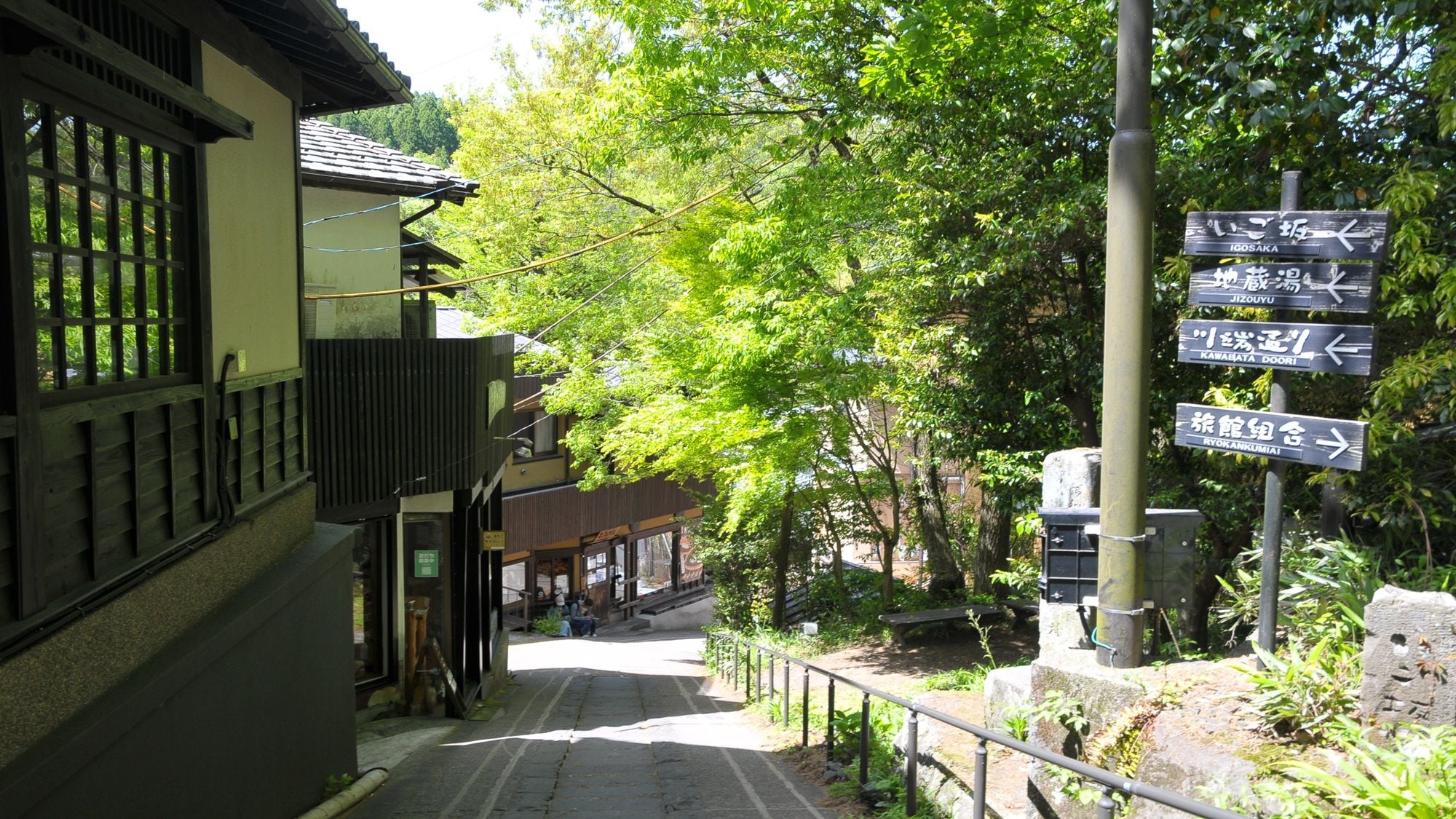 Un bâtiment japonais traditionnel, doté d’une façade en bois et d’un panneau indicateur indiquant les directions vers différents lieux.
