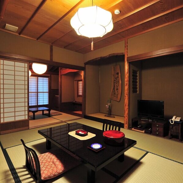 A traditional Japanese room with tatami flooring, a low table with cushions, a television, and a wooden ceiling. - Kurokawa Onsen Iyashi no Sato Kiyashiki (Minamioguni)