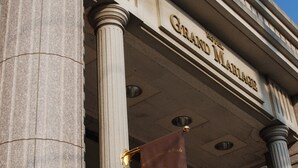 Un edificio de arquitectura clásica, con columnas y un cartel que dice 'Grand Mansion Hotel'.