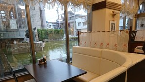 Un restaurante con zona de estar, una mesa y sillas, vista a un cuerpo de agua y una planta decorativa.