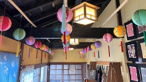 A room with hanging lanterns, a traditional Japanese lantern, and a view of the outside through a window. - Oyado Sakura Gojo Station (Gojo)