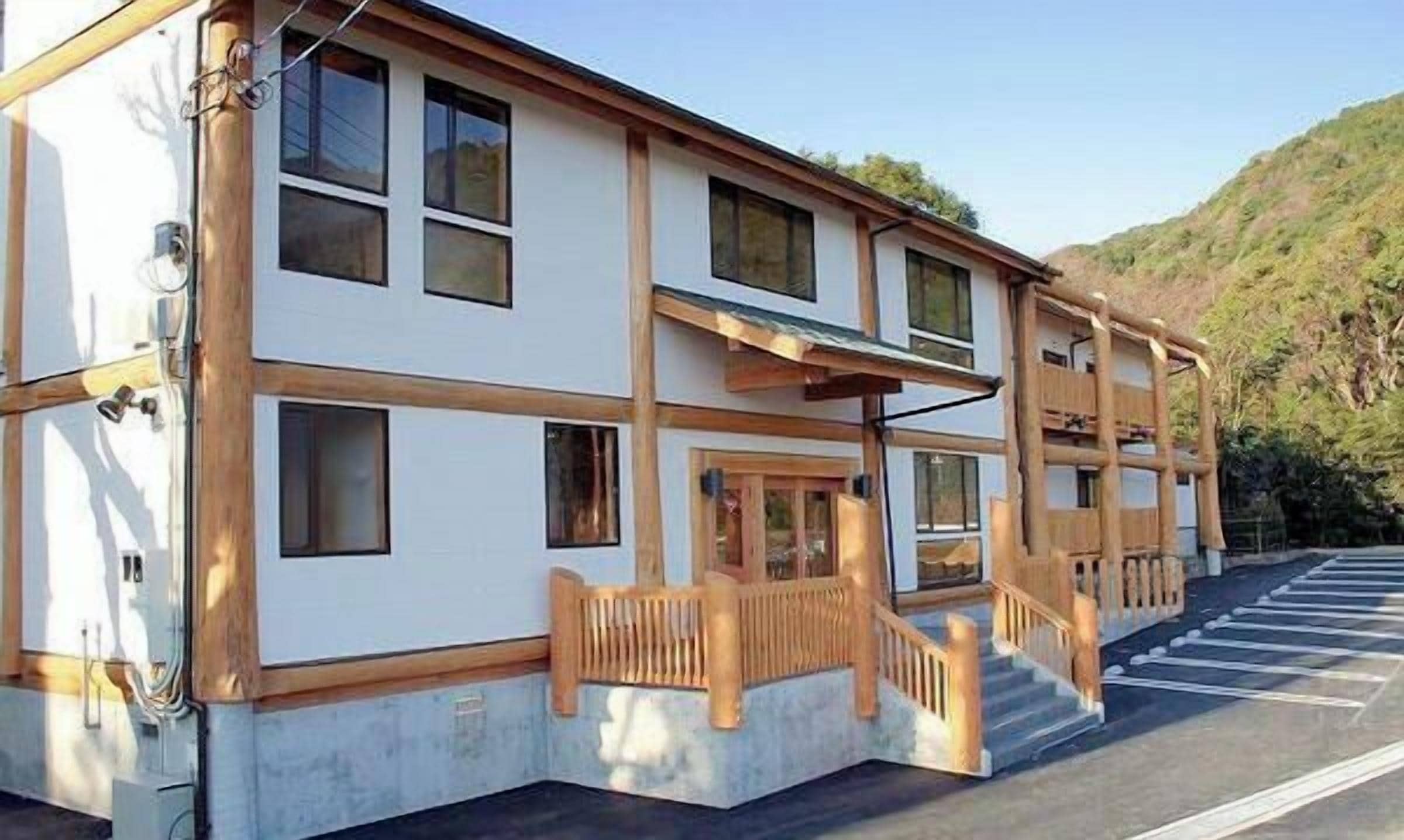 A two-story building with a flat roof, large windows, and a wooden staircase leading to the entrance.