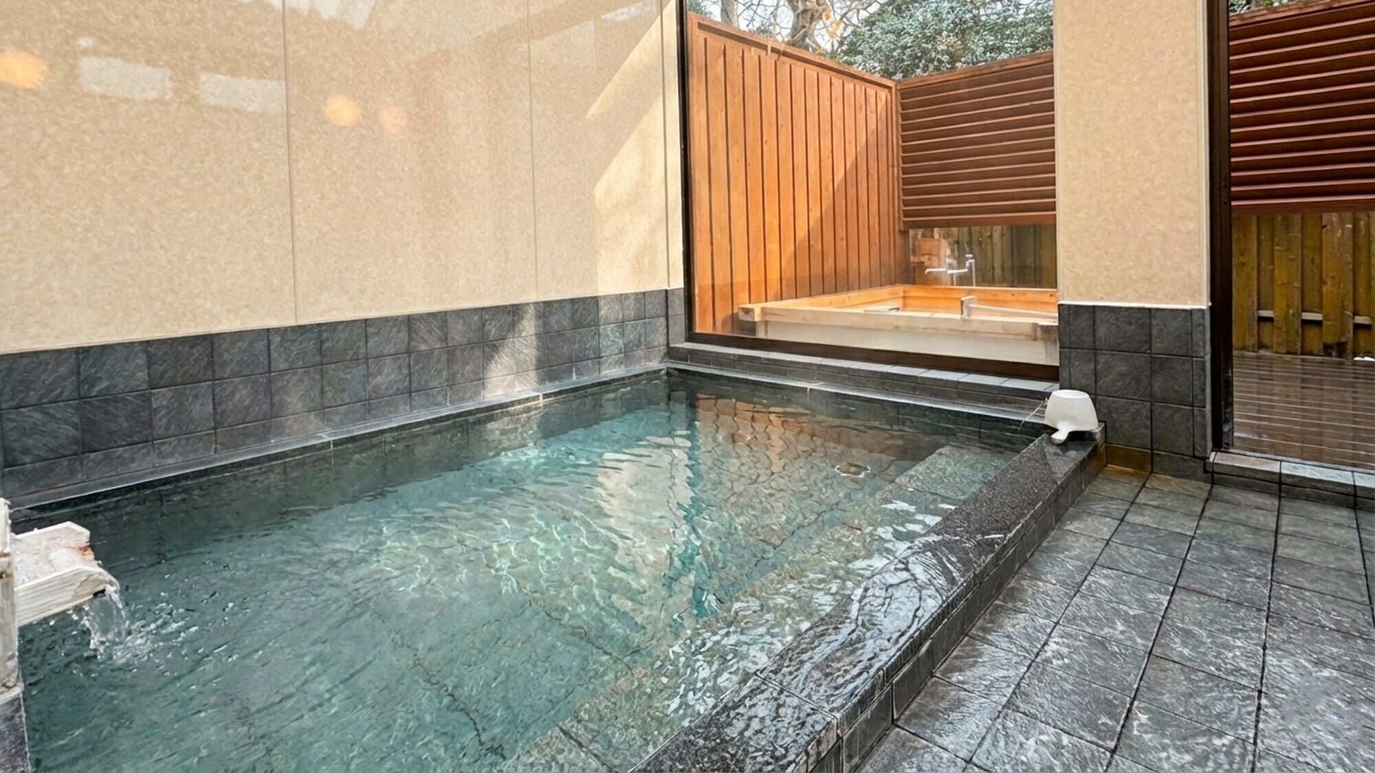 A spa area with a hot tub, tiled walls, and a wooden deck.