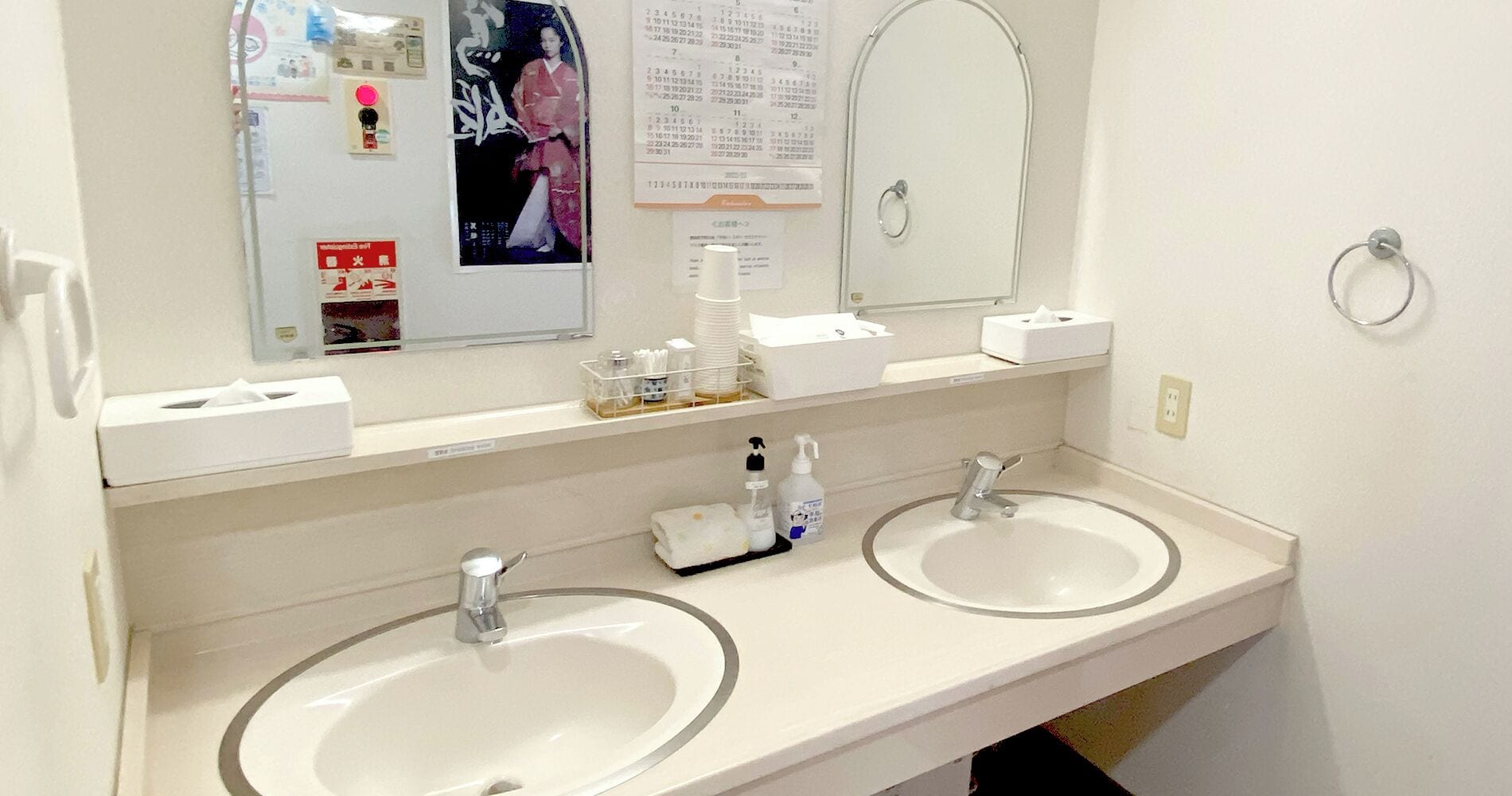 Un baño con dos lavamanos, un espejo y un calendario en la pared.