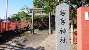 A stone monument with Japanese characters, a traditional torii gate, and a red fence.