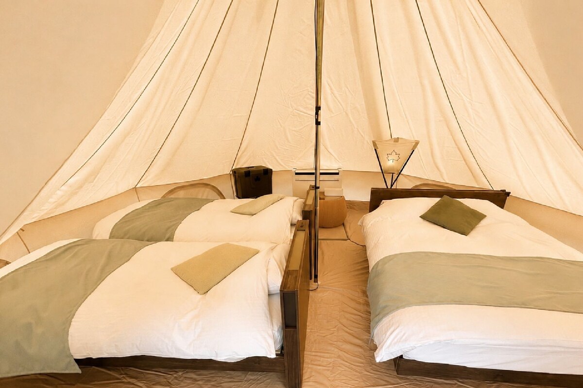 A tent with two beds, each with pillows and a blanket.