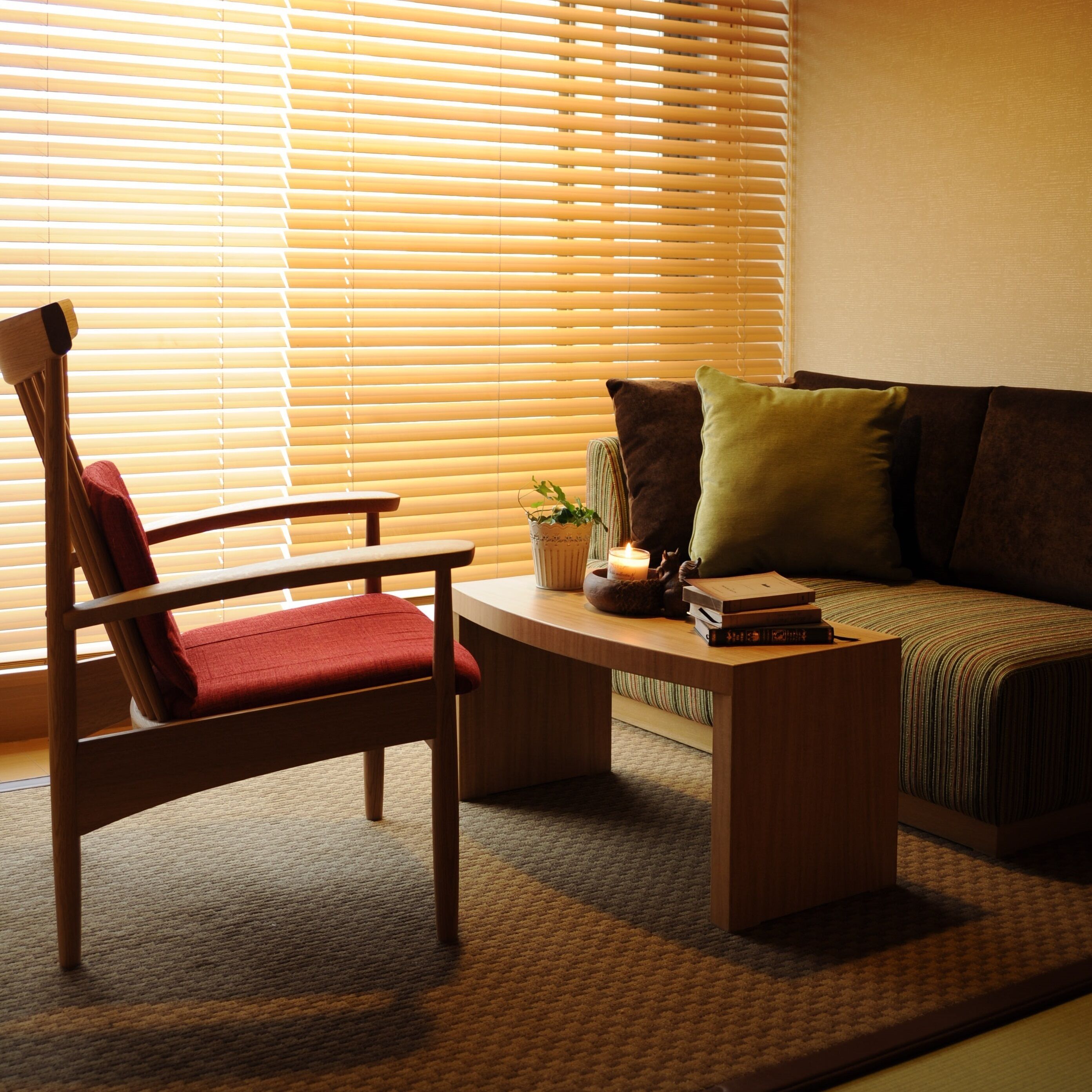 A living room with a wooden chair, a sofa, a coffee table, and a window with blinds.