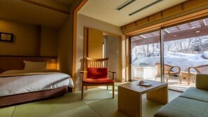 A hotel room with a bed, a chair, a small table, and a sofa.