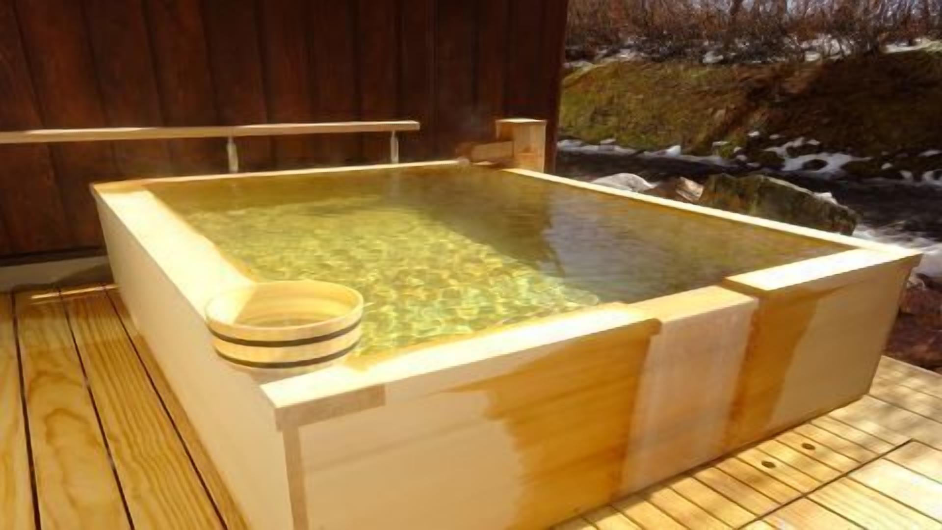 A wooden hot spring bath with a wooden deck surrounding it.