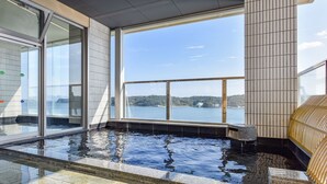 A spa area with a large window offering a view of a body of water and hills. - Fukujuso Onsen Ryokan (Shima)