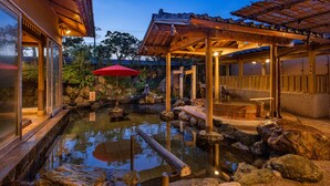A traditional Japanese onsen with a wooden bath, a red umbrella, and a stone pathway. - Fukujuso Onsen Ryokan (Shima)