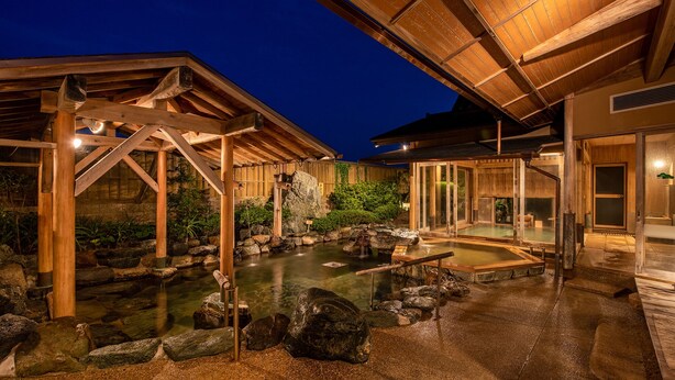 A traditional Japanese onsen with wooden structures, a rock garden, and a clear water bath area. - Fukujuso Onsen Ryokan (Shima)