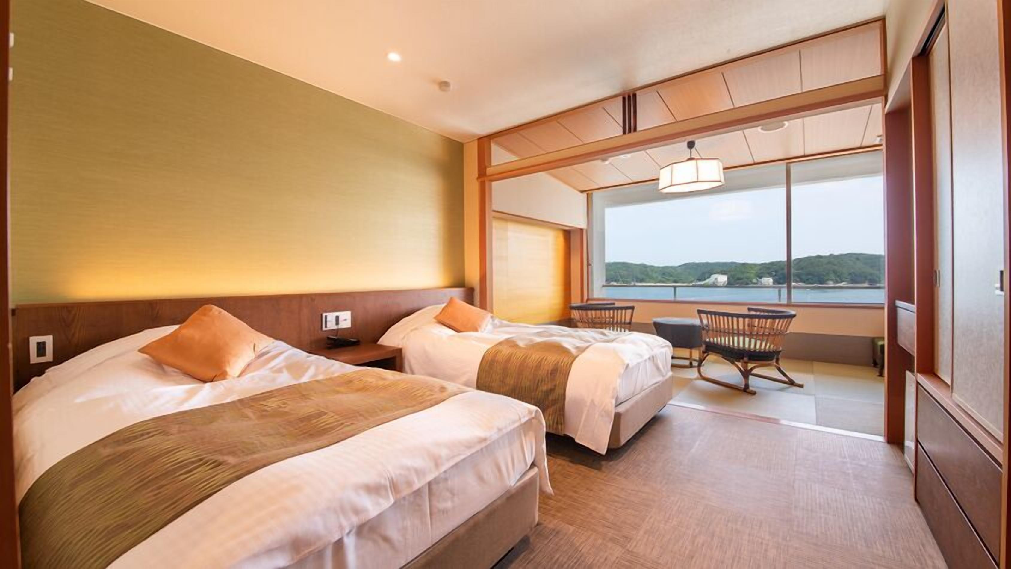 Une chambre d’hôtel avec deux lits, une petite table, des chaises et une grande fenêtre donnant sur un beau paysage.