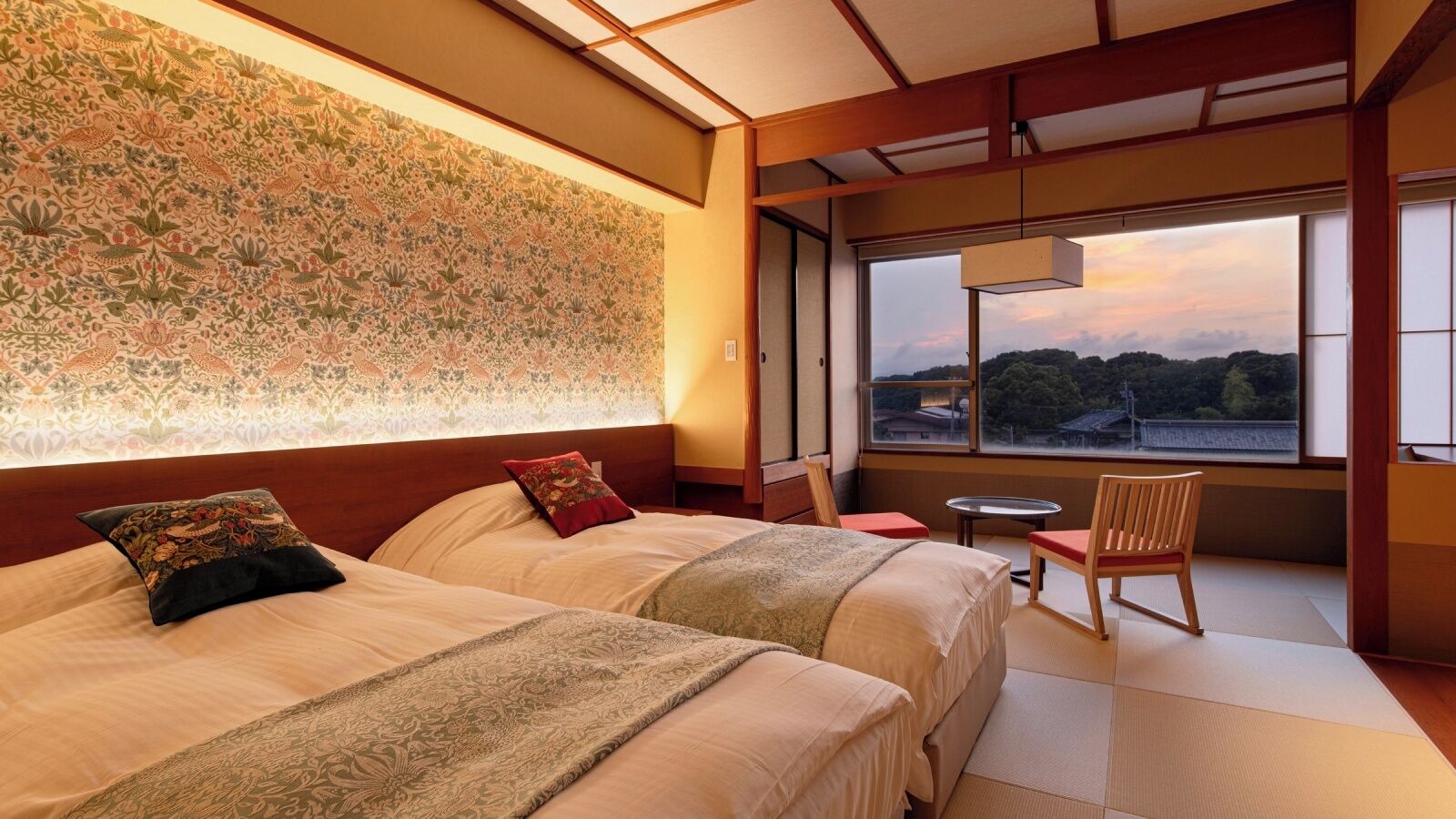 Une chambre d’hôtel avec deux lits, une vue sur le paysage et un sol traditionnel japonais recouvert de tatamis.