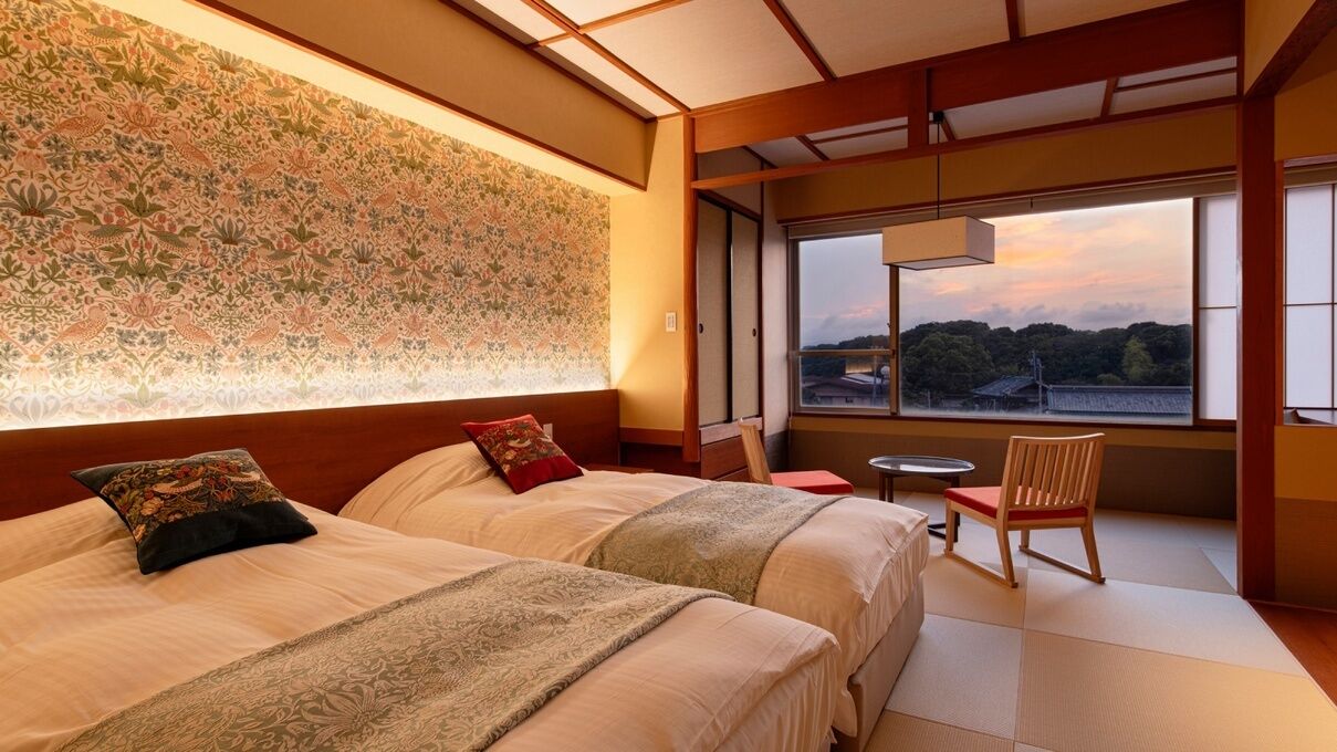 Una habitació d'hotel amb dos llits, vista al paisatge i una paret d'estil japonès tradicional.