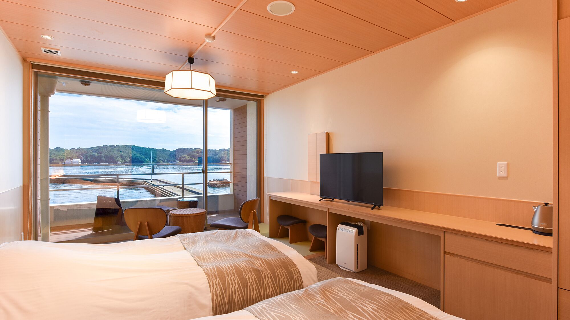 Une chambre d’hôtel équipée d’un lit, d’un bureau, d’une télévision et offrant une vue sur une étendue d’eau.