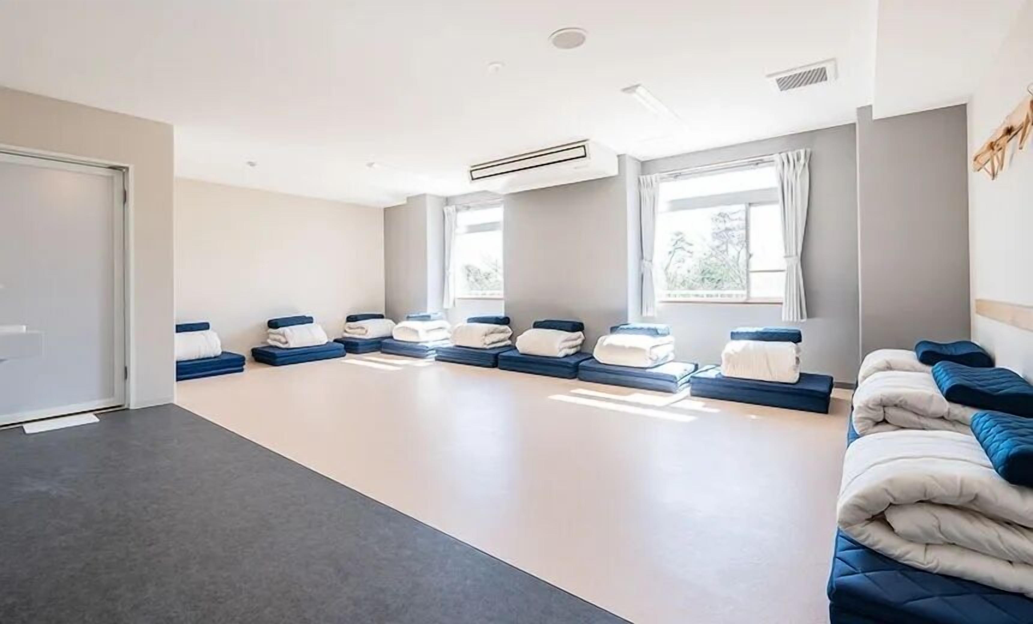 A room with a large, open floor plan, a ceiling fan, and a window with curtains.