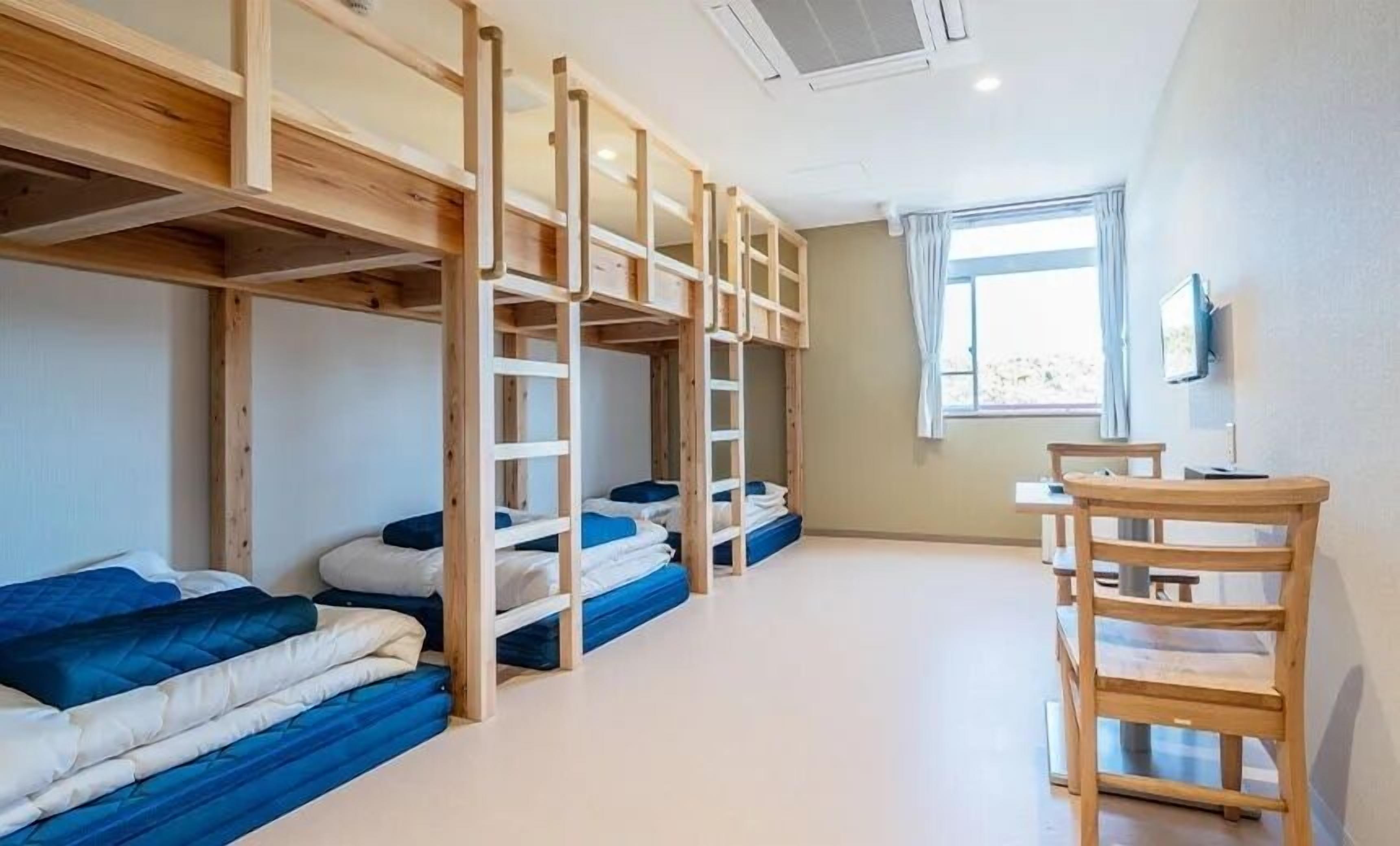 A room with bunk beds, a desk, and a window.