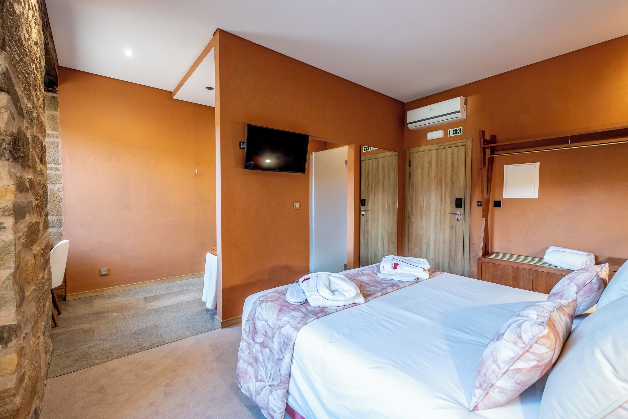 Habitación de hotel con dos camas, un televisor de pantalla plana, un equipo de aire acondicionado y un armario de madera.