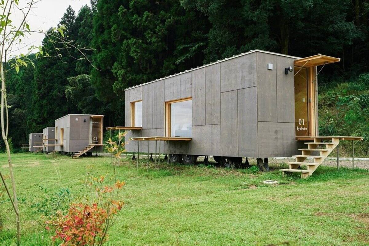 Une série de cabanes modulaires dotées de murs extérieurs, de fenêtres et d’escaliers en bois menant à l’entrée.