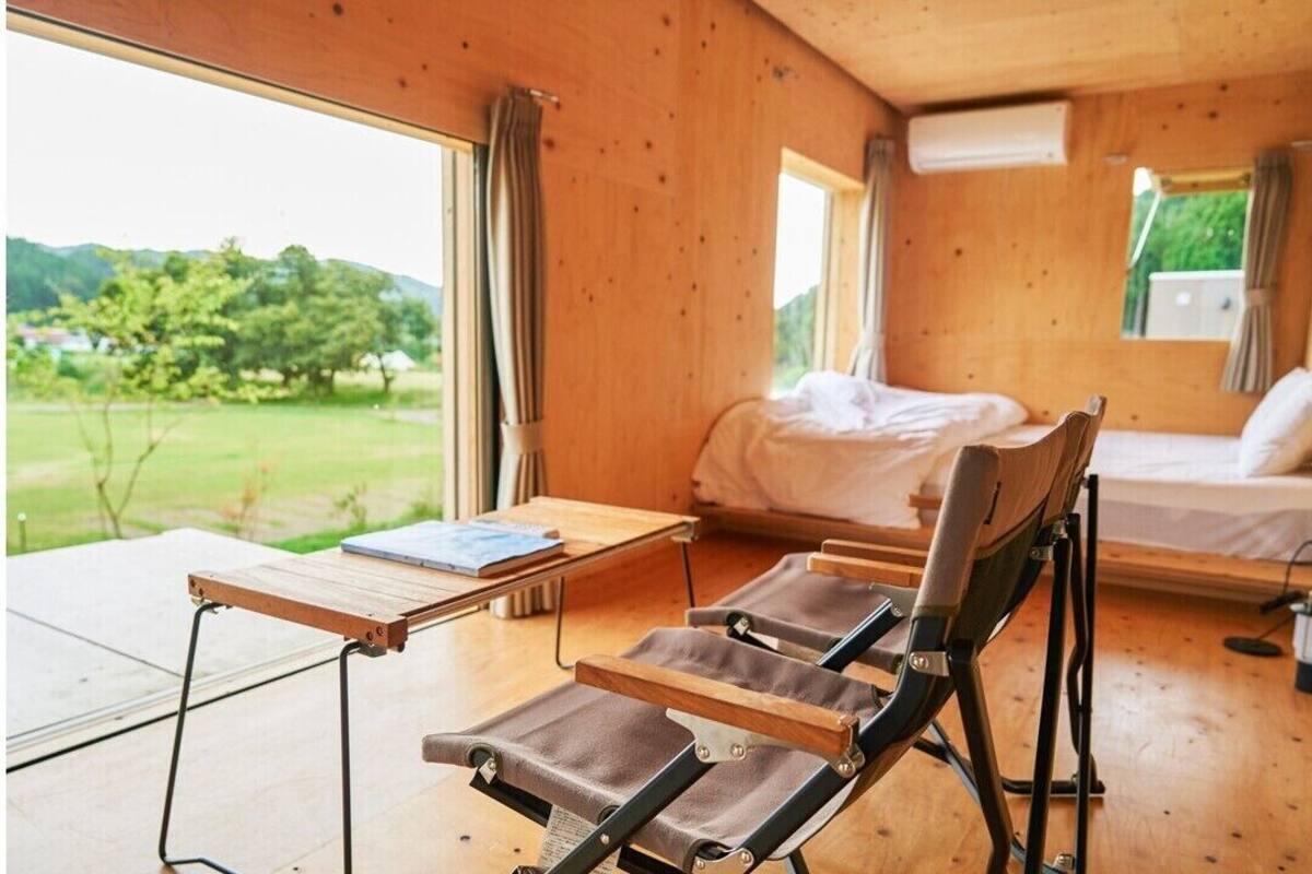 Un intérieur en bois comprenant un lit, une table et deux chaises.