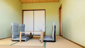 A room with tatami mats, a low wooden table, and two tatami mats with cushions. - Bluebird Hotel (Fujikawaguchiko)