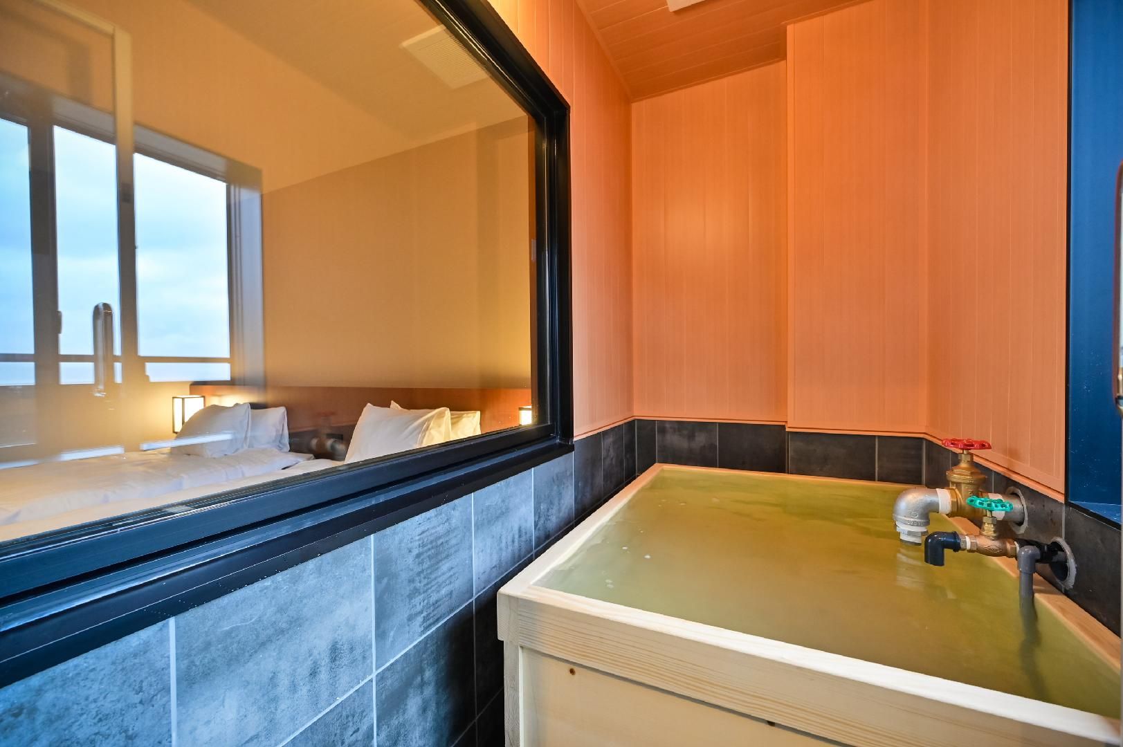 Un baño con un espejo grande, una bañera y un lavamanos con grifo.