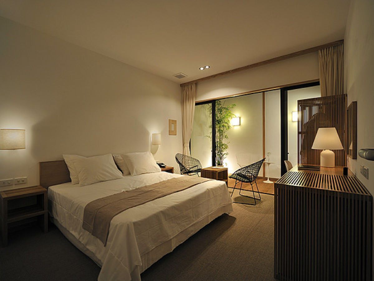 Een hotelkamer met een bed, een stoel, een bureau en een lamp.