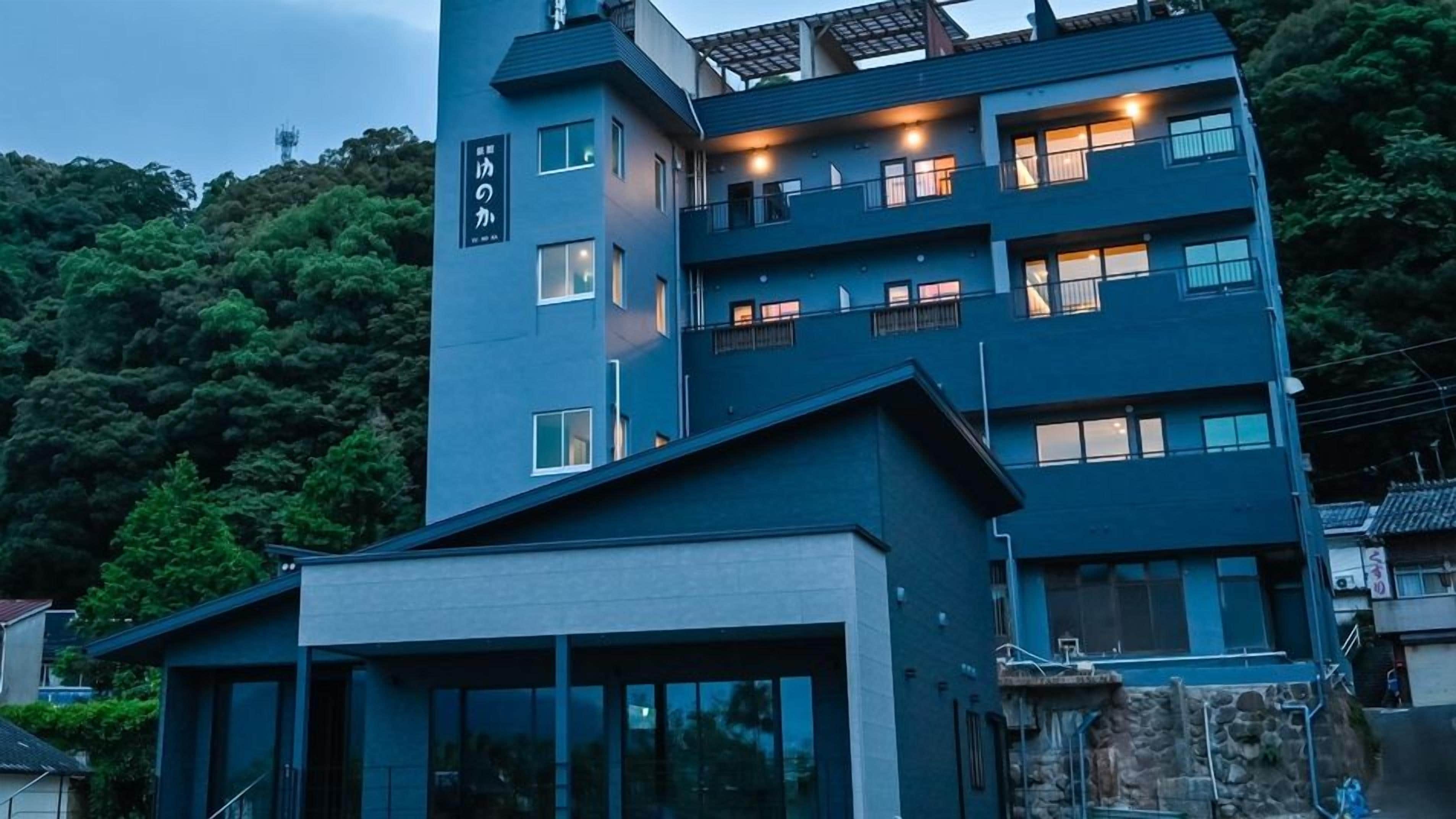 Un edificio de varios pisos con balcones y ventanas, rodeado de árboles.