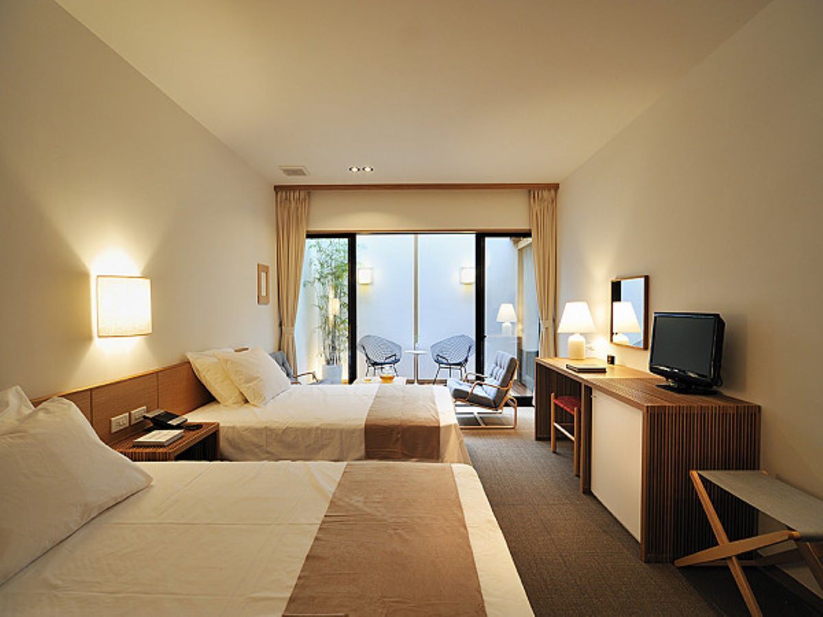 Een hotelkamer met twee bedden, een bureau met een computer, een stoel en een televisie.