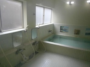 A bathroom with a bathtub, a window, and a shower. - Marutaka Kanko Ryokan (Kitaibaraki)