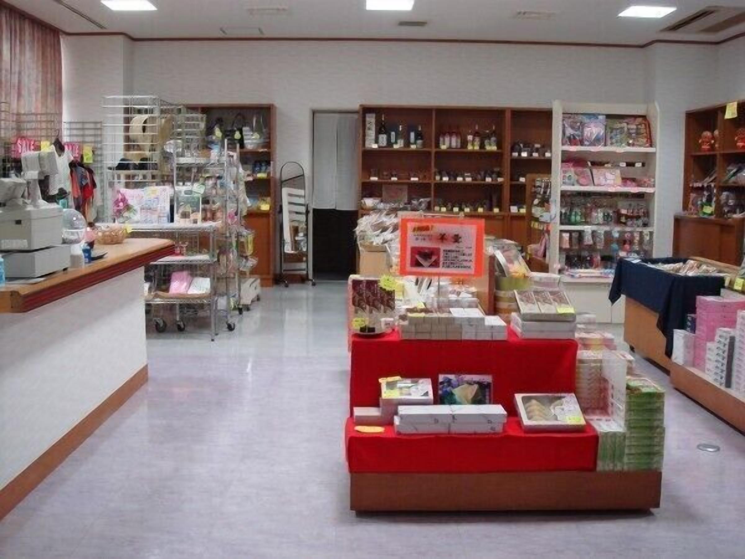 A pharmacy with shelves stocked with various products, a counter with a cash register, and a display of packaged goods.