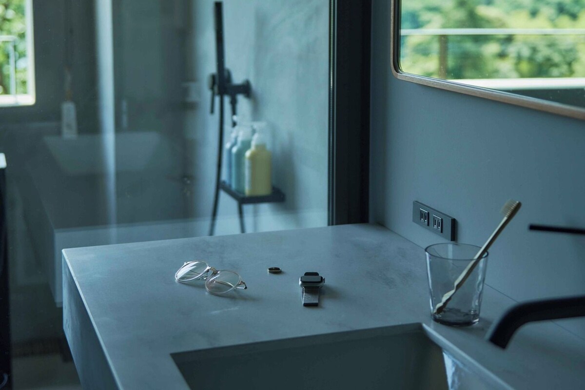 A modern bathroom with a large window, a sink, and a mirror.